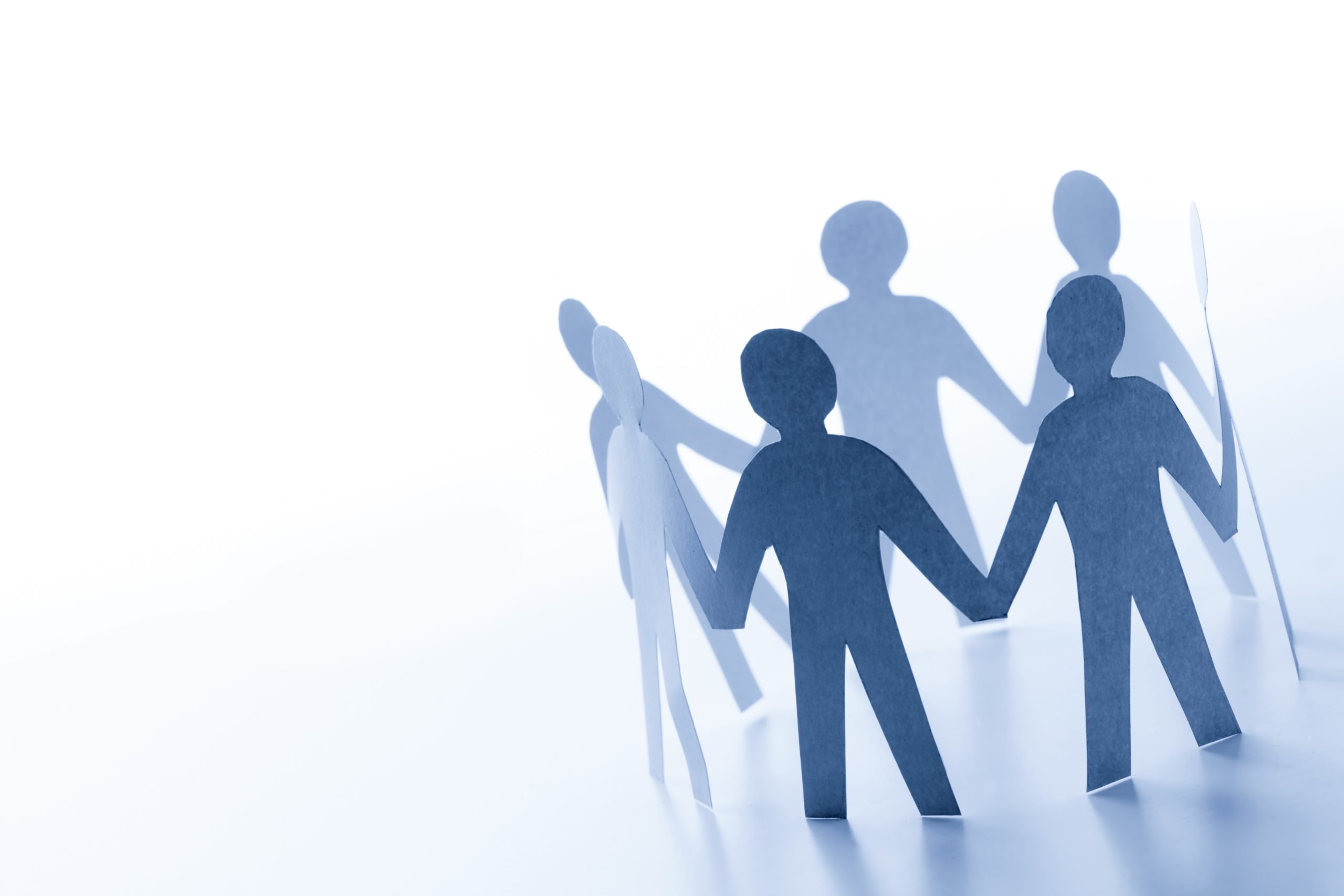 Paper people standing together hand in hand in support.