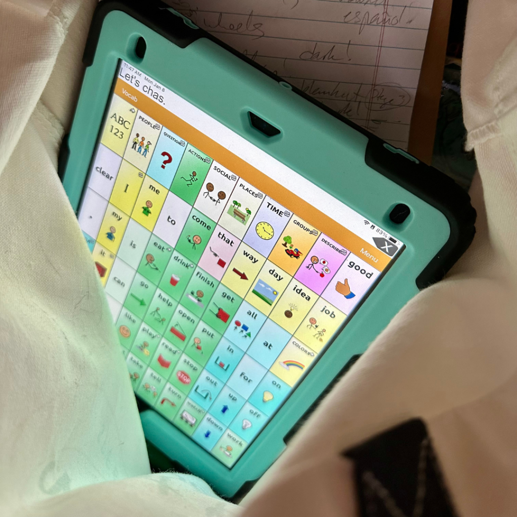 Above view of a canvas bag with an iPad screen showing a page from a communication device or AAC device.